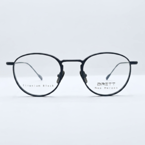 Round black eyeglasses with a metal bridge; left lens shows 'Titanium Block' and right lens shows 'BRETT Neo Heroes' branding.