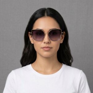 Portrait of a woman with dark hair wearing oversized gradient sunglasses and a white T-shirt against a gray background.