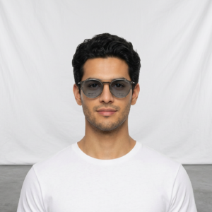 Man wearing sunglasses and a white T-shirt standing against a light backdrop.
